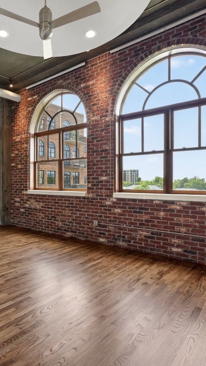 Sunlight through large arched windows in an exposed-brick loft