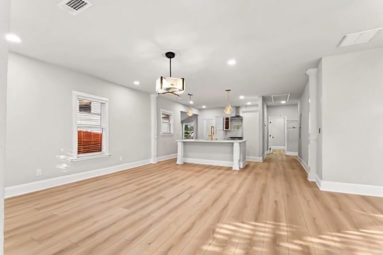 A bright open living space with timber floors and a kitchen beyond
